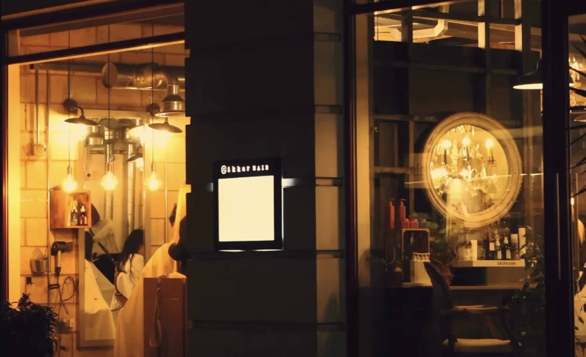 Ikkar studio at night — Edison bulbs and chandelier visible through the storefront windows